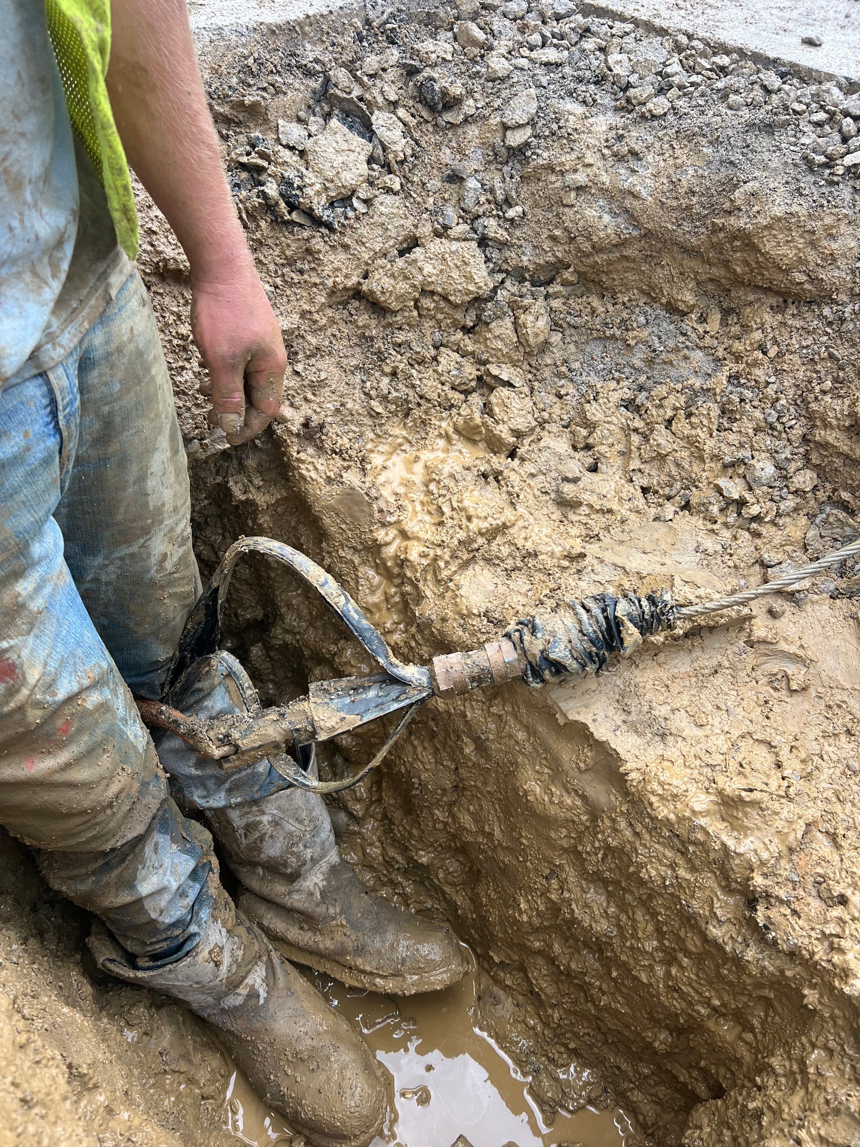 Worker digging muddy excavation site